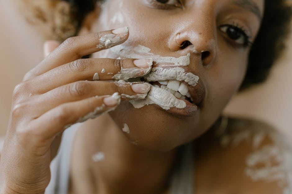 Une femme appliquant un masque d'argile sur son visage en gros plan, mettant en valeur sa routine de soin.