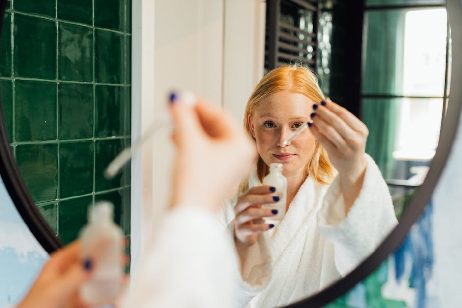 Femme adulte appliquant un sérum de soin visage en robe de chambre devant un miroir de salle de bains